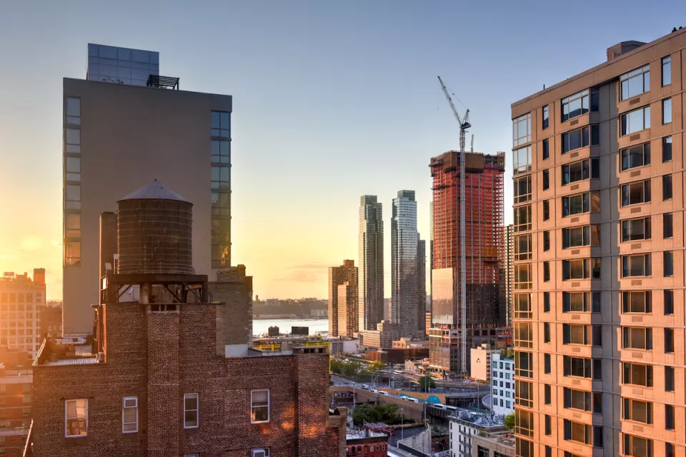 View of high-rise buildings and construction cranes in midtown Manhattan against sunset sky